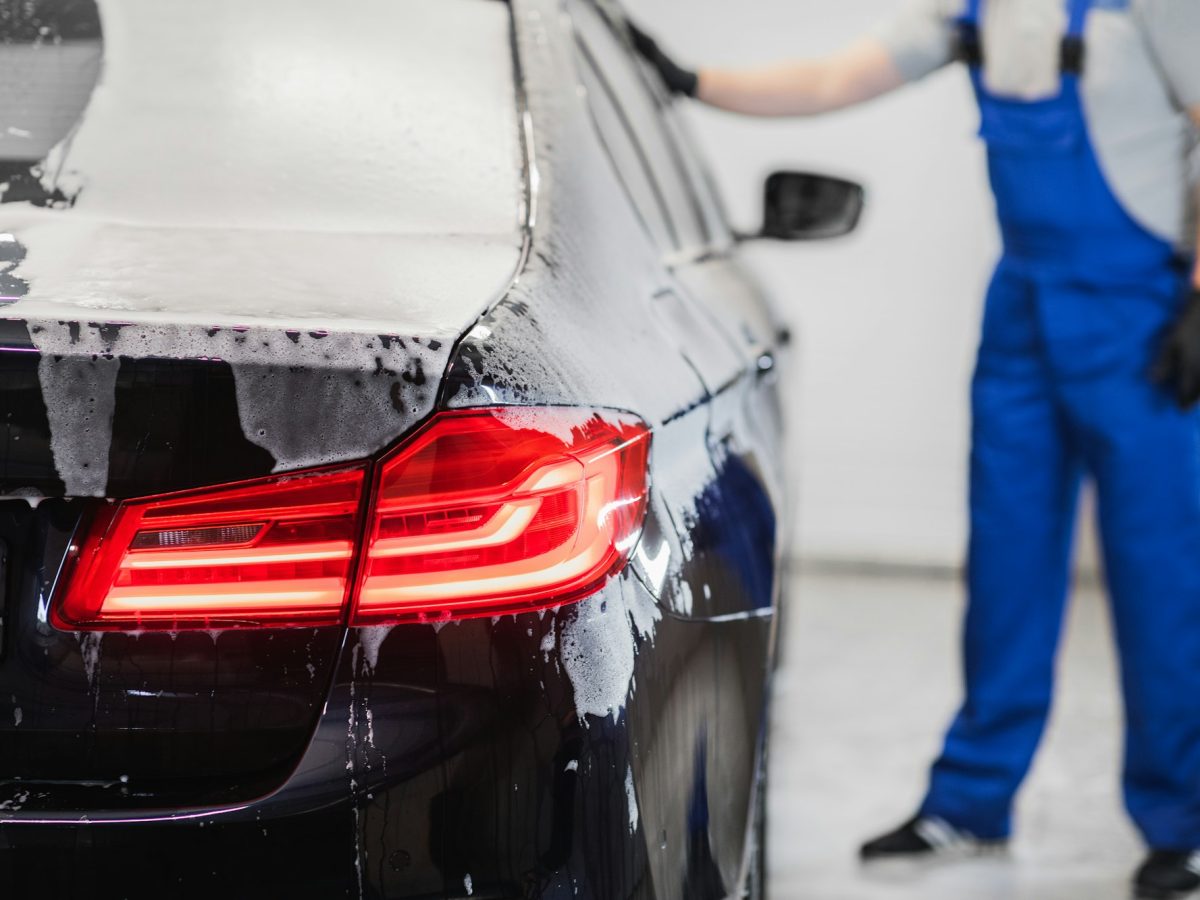 Man washing the car after shampooing the bodywork wiping the car surface with a special cleaning