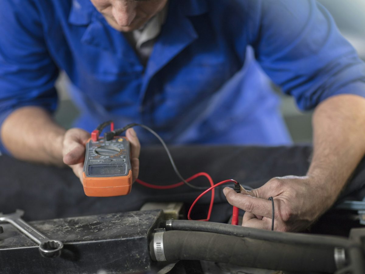 Mechanic using a multimeter on a vehicle.